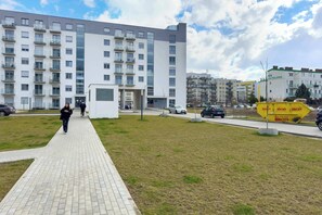 A modern building with multiple balconies and a paved walkway. - Stylish Apartment with Balcony | Parking | Close to Malta Lake (Poznań)