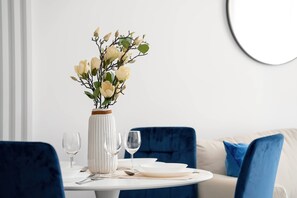A dining table with a vase of flowers, two wine glasses, and a plate. - Stylish Apartment with Balcony | Parking | Close to Malta Lake (Poznań)
