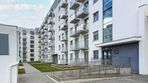 Un immeuble d’appartements moderne doté de nombreux balcons, d’une entrée sécurisée et d’un chemin piétonnier dallé.