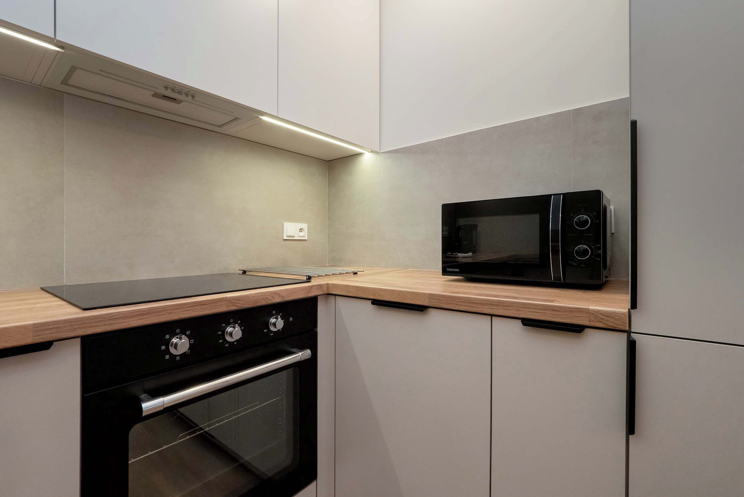 A modern kitchen with a built-in oven, a microwave, and a wooden countertop.