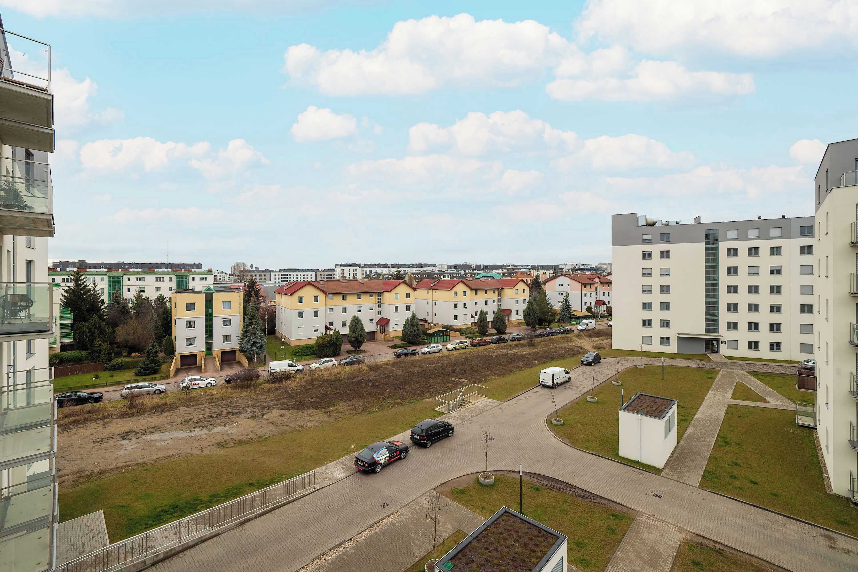 A residential area with multi-story apartment buildings, a parking lot, and a grassy area.