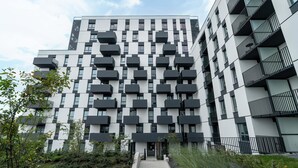 A modern multi-story building with a geometric facade, balconies, and a central entrance. - Modern Apartment in Poznan | Balcony, Parking (Poznań)