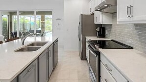 A modern kitchen with a central island, stainless steel appliances, and a view of the outdoors.