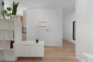 Quarto moderno e minimalista com armários brancos, piso de madeira e porta com listras horizontais.
