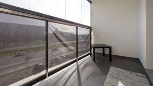 A balcony with a view of a road and a building in the distance.