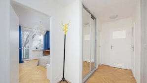 A modern room with a wooden herringbone floor, a standing lamp, and a sliding glass door leading to another room.