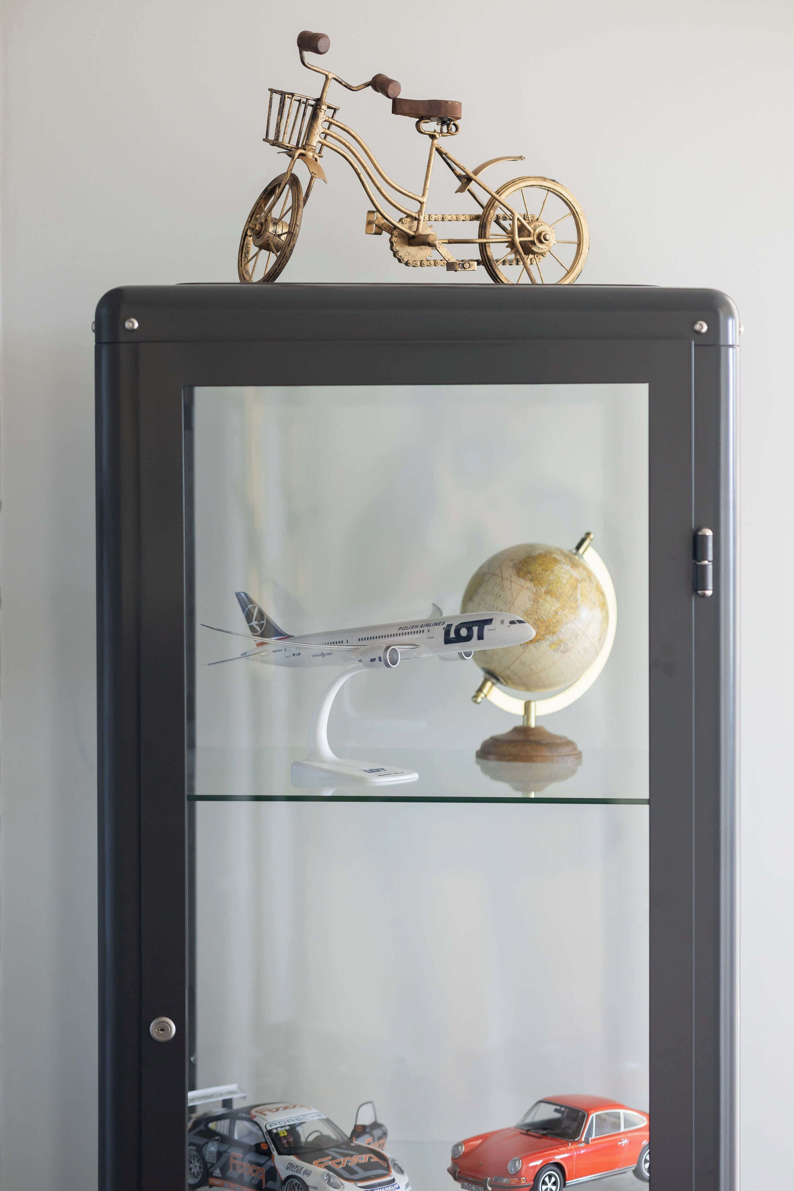 A display cabinet with a bicycle on top, a model airplane, and a globe.