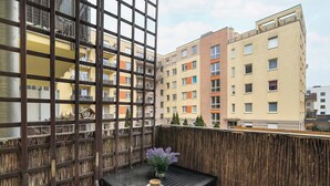 A balcony with a wooden fence, a small table with a vase of flowers, and a cup.
