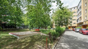 A paved pathway alongside a grassy area with a red bench and a sandbox.