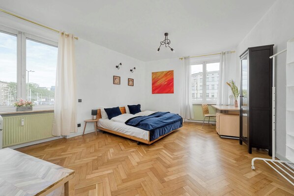 A modern bedroom with a wooden bed, a desk, and a radiator.
