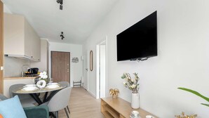 Ein modernes Wohnzimmer mit Essbereich, einem wandmontierten Flachbildfernseher und einem Holzkonsolentisch mit Dekoration.