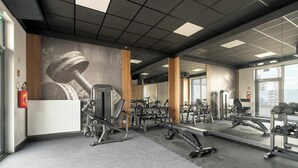 Ein Fitnessraum mit Trainingsger äten, einem großen Spiegel und Blick ins Freie.