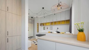 Une cuisine moderne avec des meubles blancs, un plan de travail en bois et un vase jaune orné de fleurs.