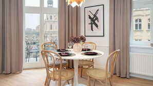 Un comedor con una mesa redonda, cuatro sillas, un florero con flores y una obra de arte enmarcada en la pared.