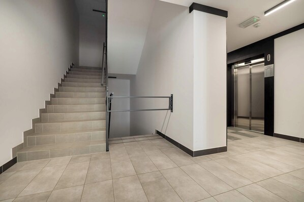 A modern interior with a staircase, elevator, and tiled flooring.