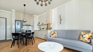 Una sala moderna con un sofá gris, una mesa de centro redonda y una zona de comedor con juego de comedor negro.