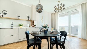 Un comedor moderno con una mesa redonda, sillas tapizadas en negro y una lámpara de araña.