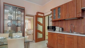 A modern kitchen with wooden cabinets, a glass dining table, and a view into the dining area.
