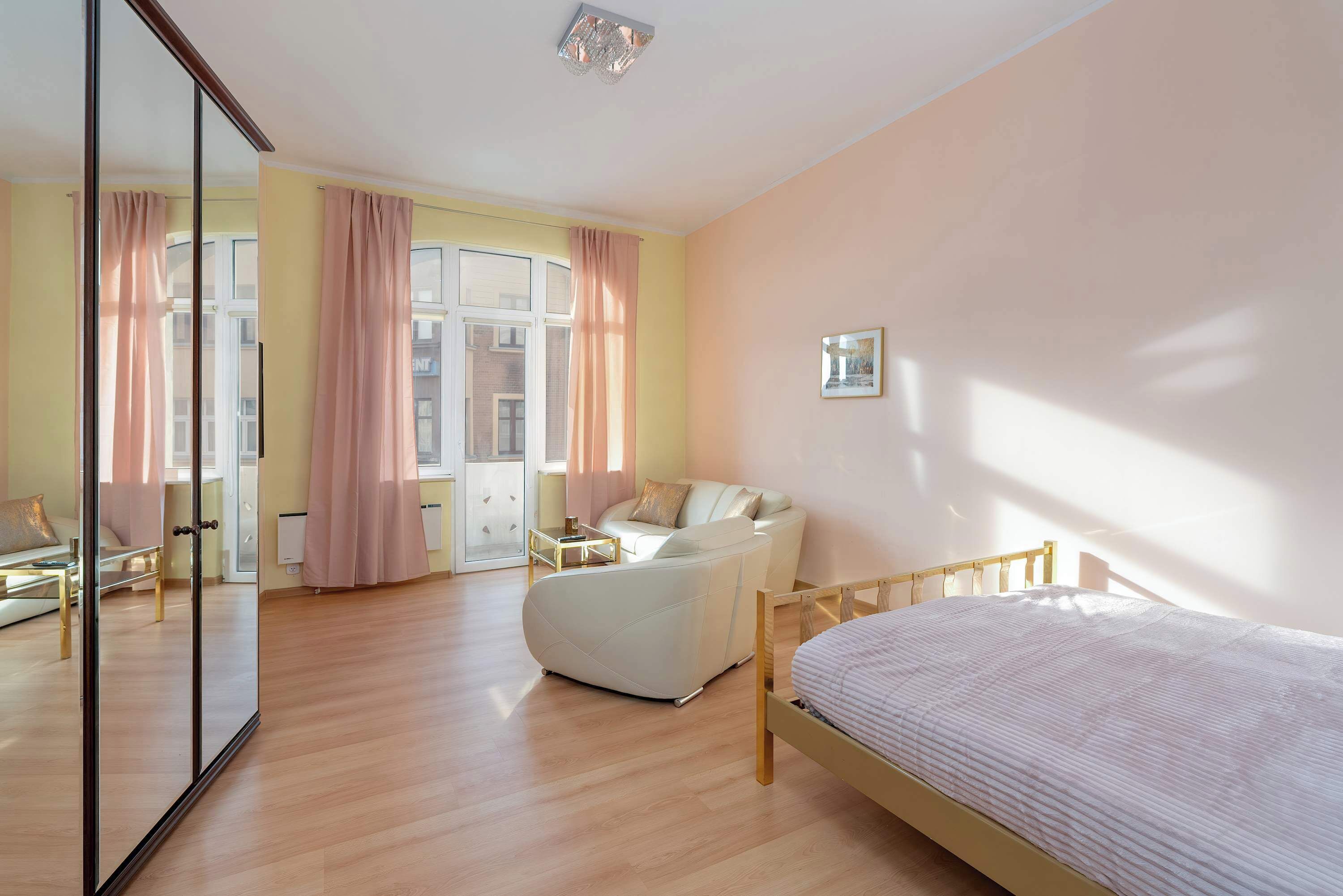 Una camera da letto con un letto, un divano, un comodino e un ampio specchio.