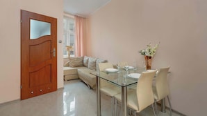 A dining area with a glass table and chairs, a sofa, and a door with a frosted glass panel.
