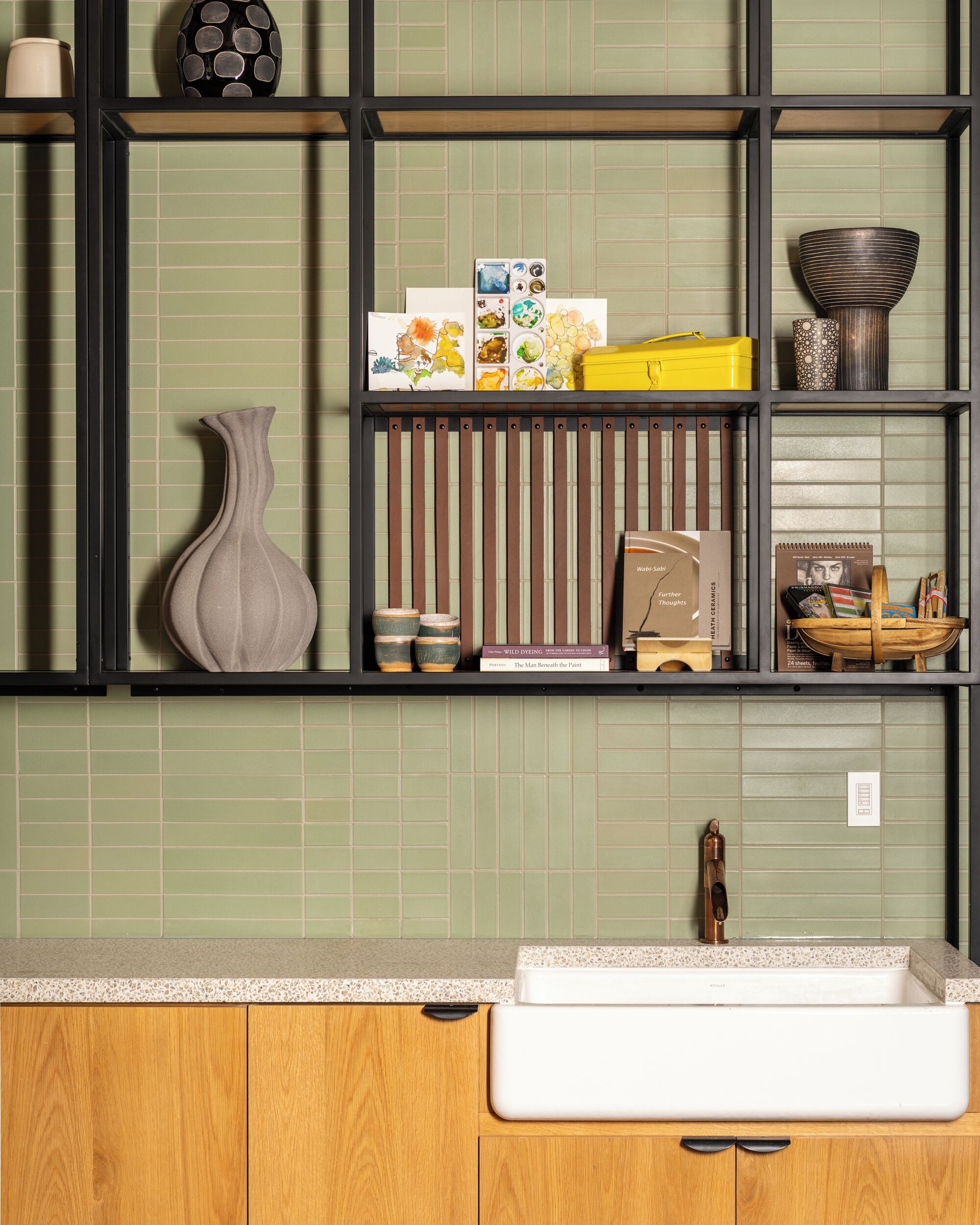 Una cocina con un lavabo blanco, armarios de madera y salpicadero de azulejos.