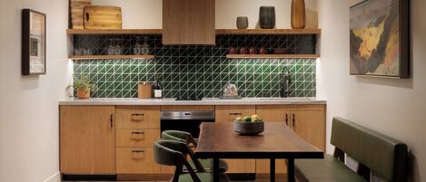 Uma cozinha moderna com armários de madeira, painel de azulejos verdes, uma mesa de jantar com cadeiras e um banco.