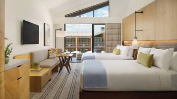 A modern hotel room with two beds, a desk, and a view of the building's exterior.