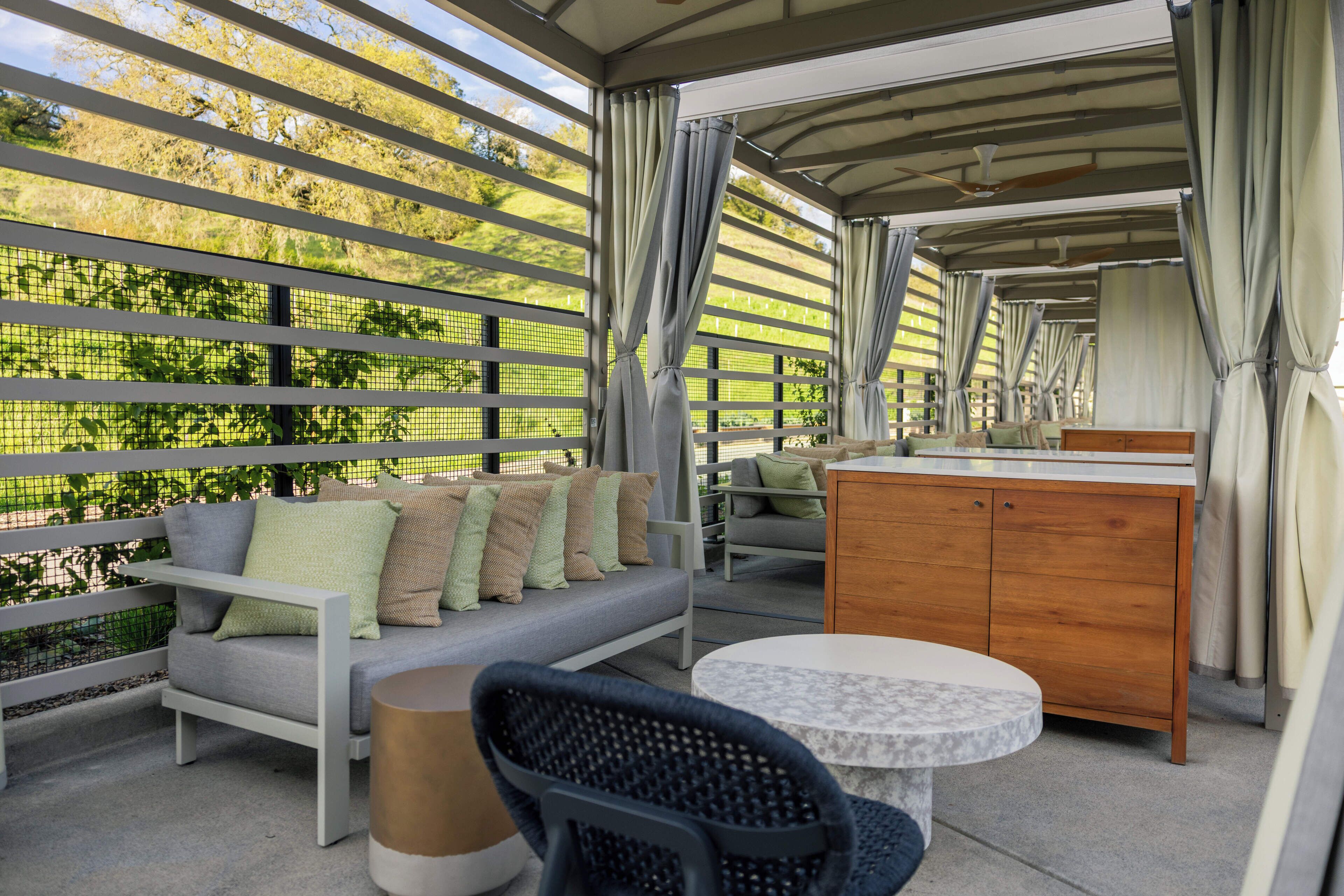 An outdoor patio with a sofa, chairs, a table, and a wooden cabinet.