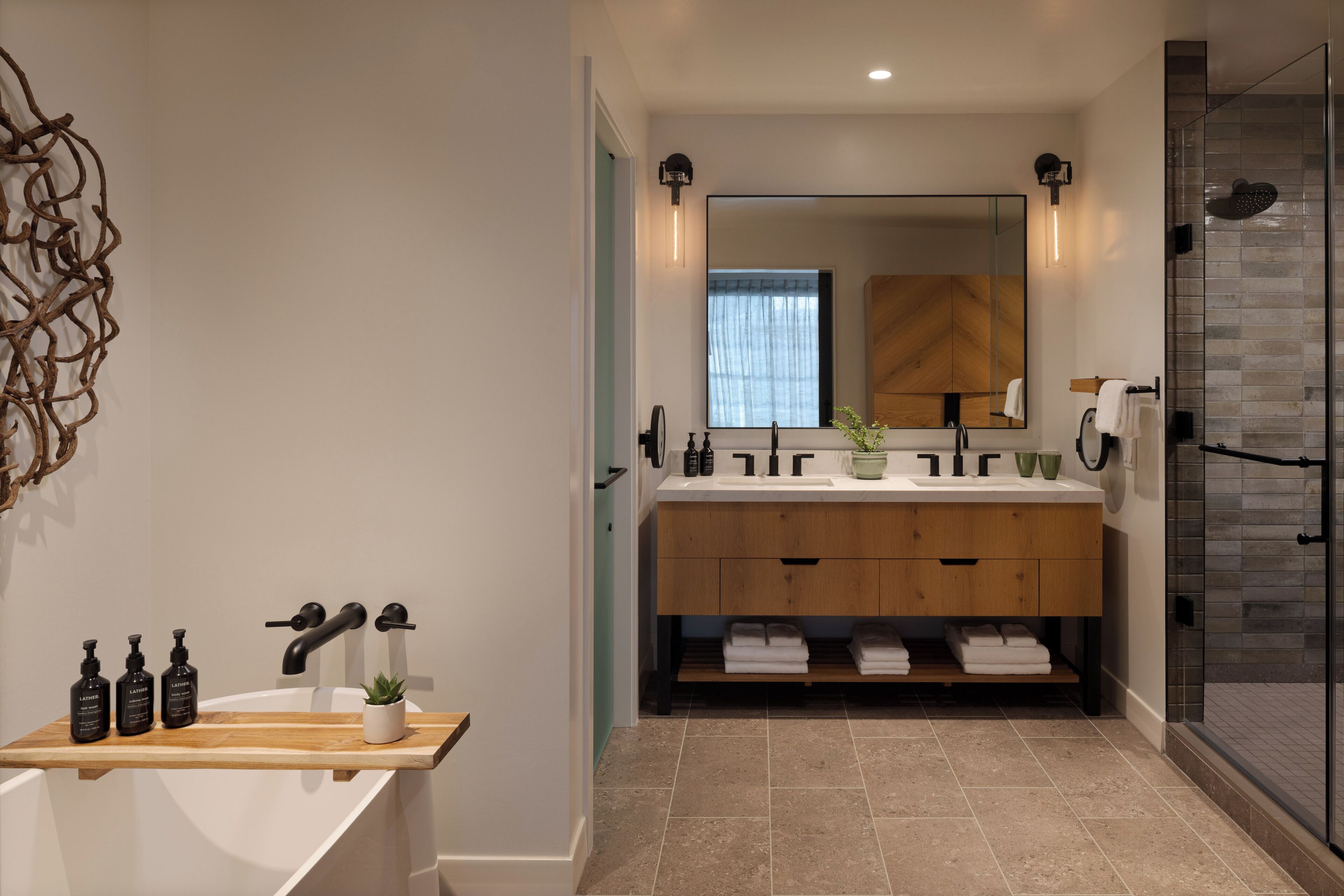 A modern bathroom with a freestanding bathtub, a double vanity with a mirror, and a glass shower enclosure.
