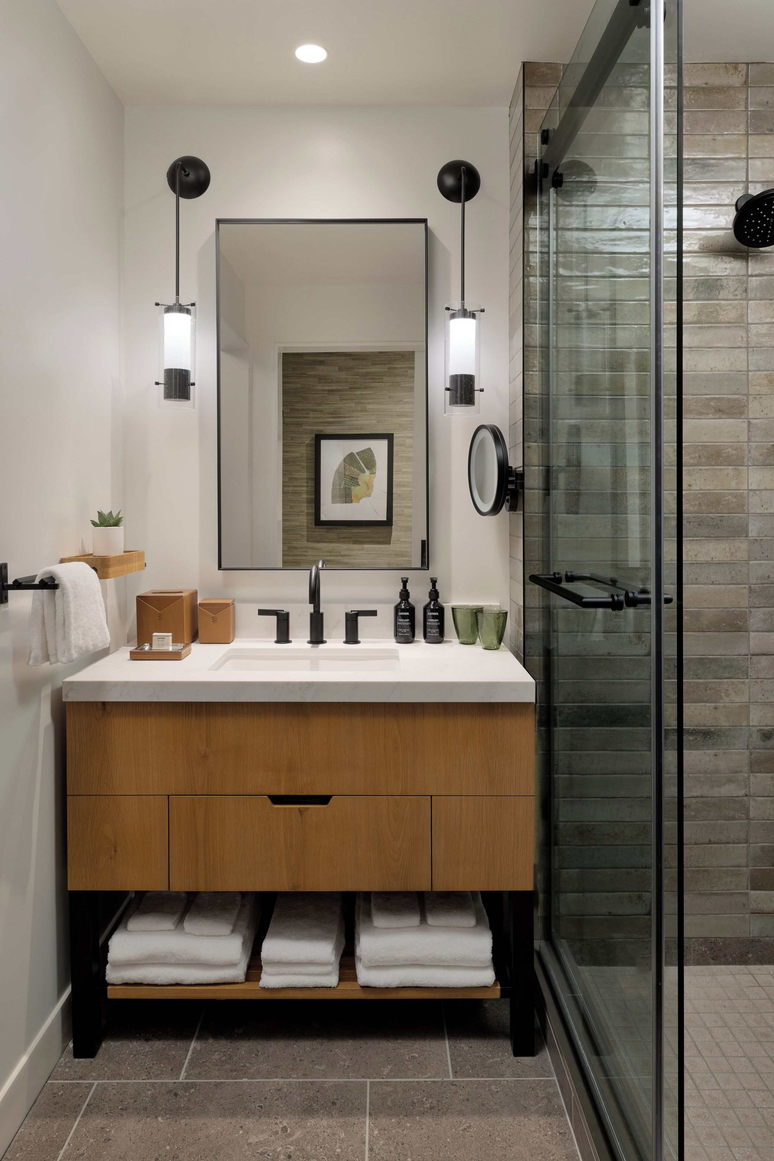Une salle de bain moderne avec un meuble-lavabo en bois, un grand miroir et une cabine de douche en verre.