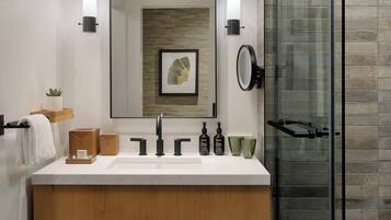 Une salle de bain moderne avec un meuble-lavabo en bois, un grand miroir et une cabine de douche en verre.