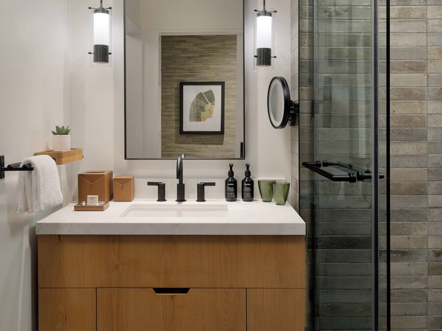 Une salle de bain moderne avec un meuble-lavabo en bois, un grand miroir et une cabine de douche en verre.