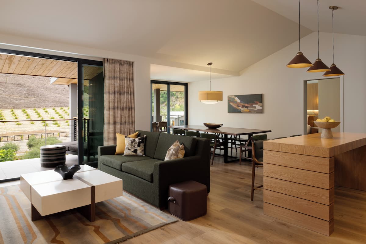 A modern living room with a sofa, coffee table, and a dining area with a table and chairs.