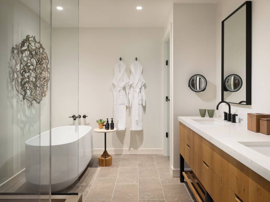 Un baño moderno con una bañera independiente, un tocador de madera y un espejo grande.