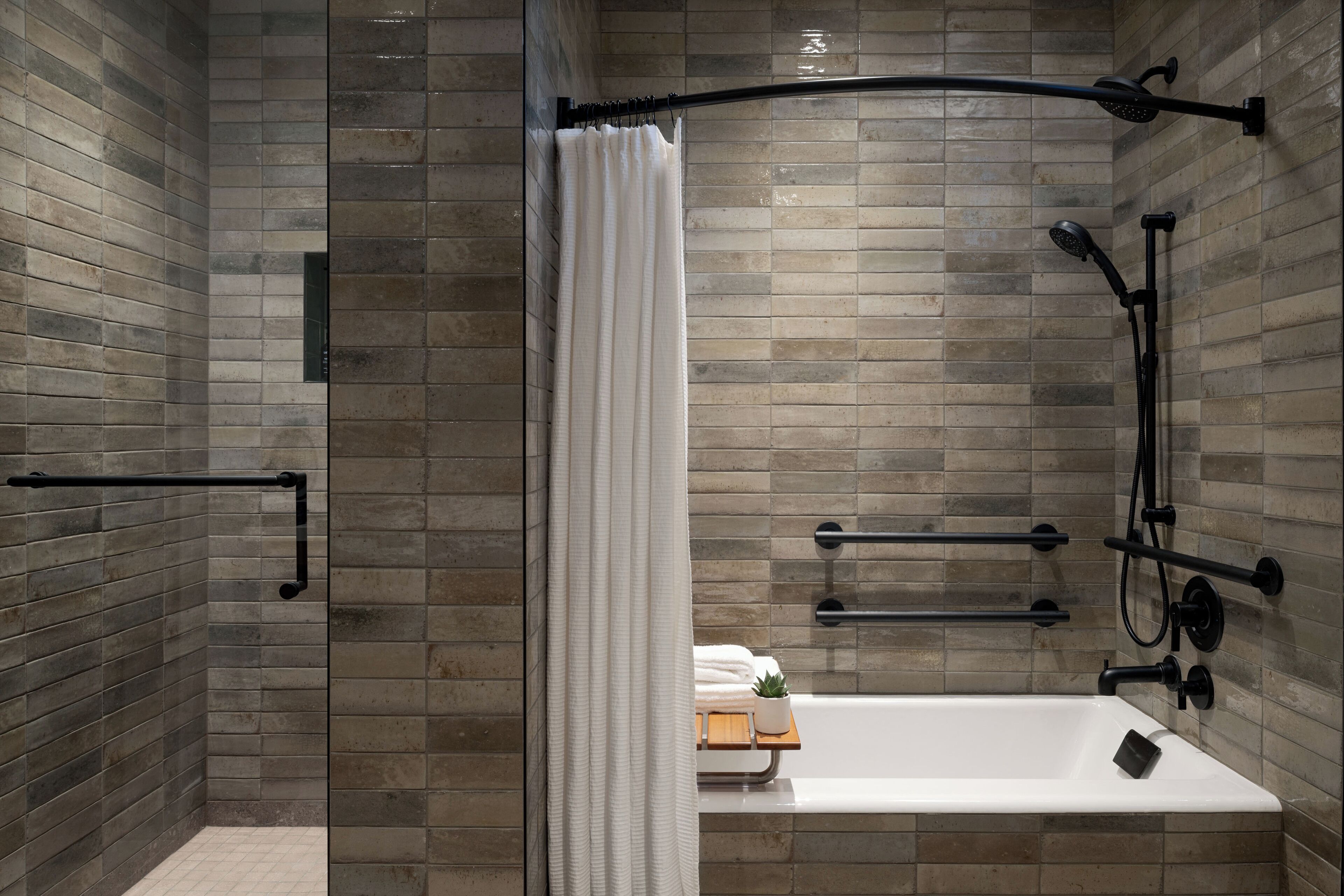 A modern bathroom with a glass-enclosed shower, a white bathtub, and a towel rack.