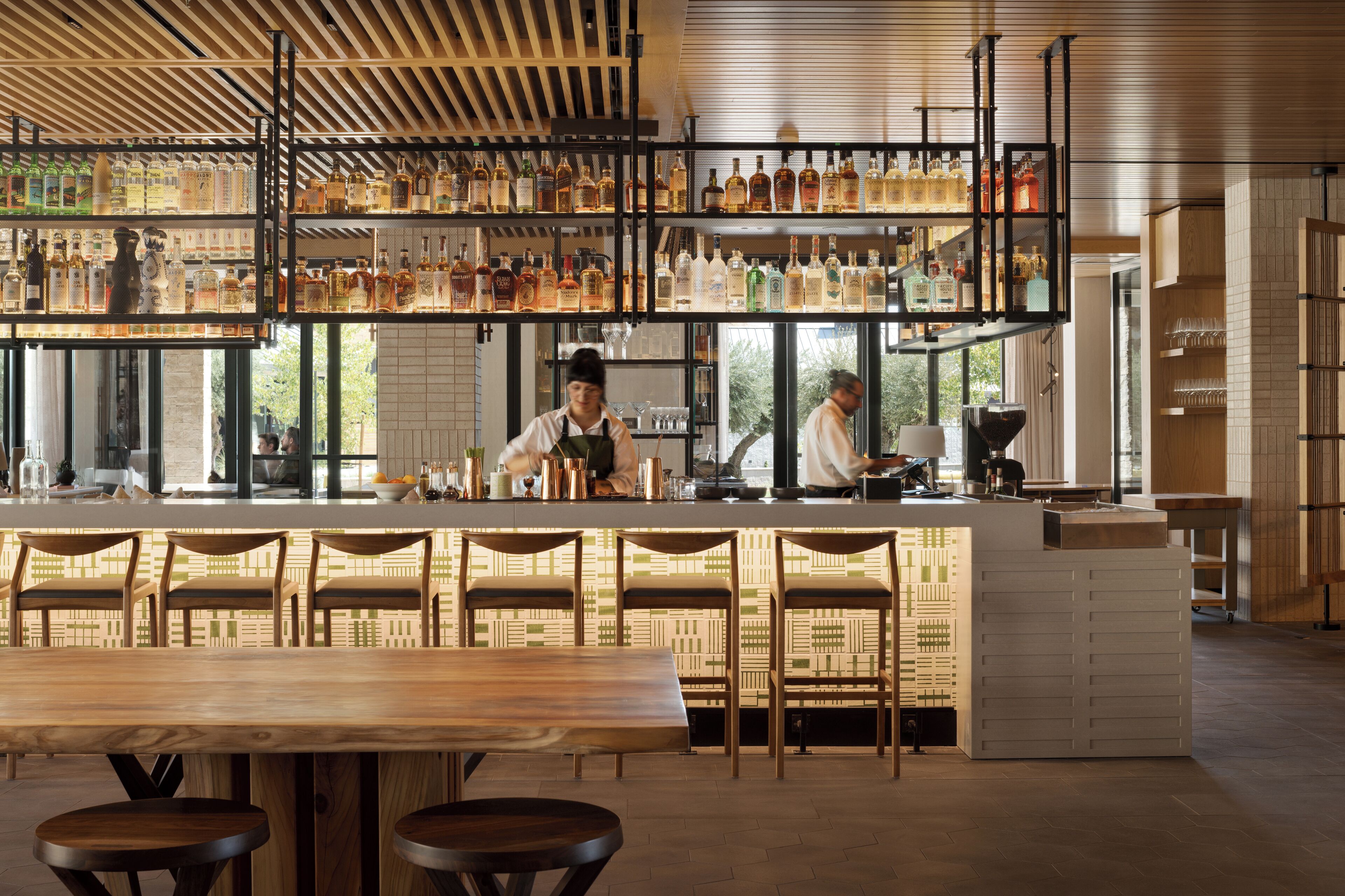 A bar area with multiple shelves of bottles, a bar counter, and seating.