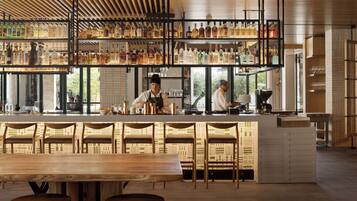 A bar area with multiple shelves of bottles, a bar counter, and seating.