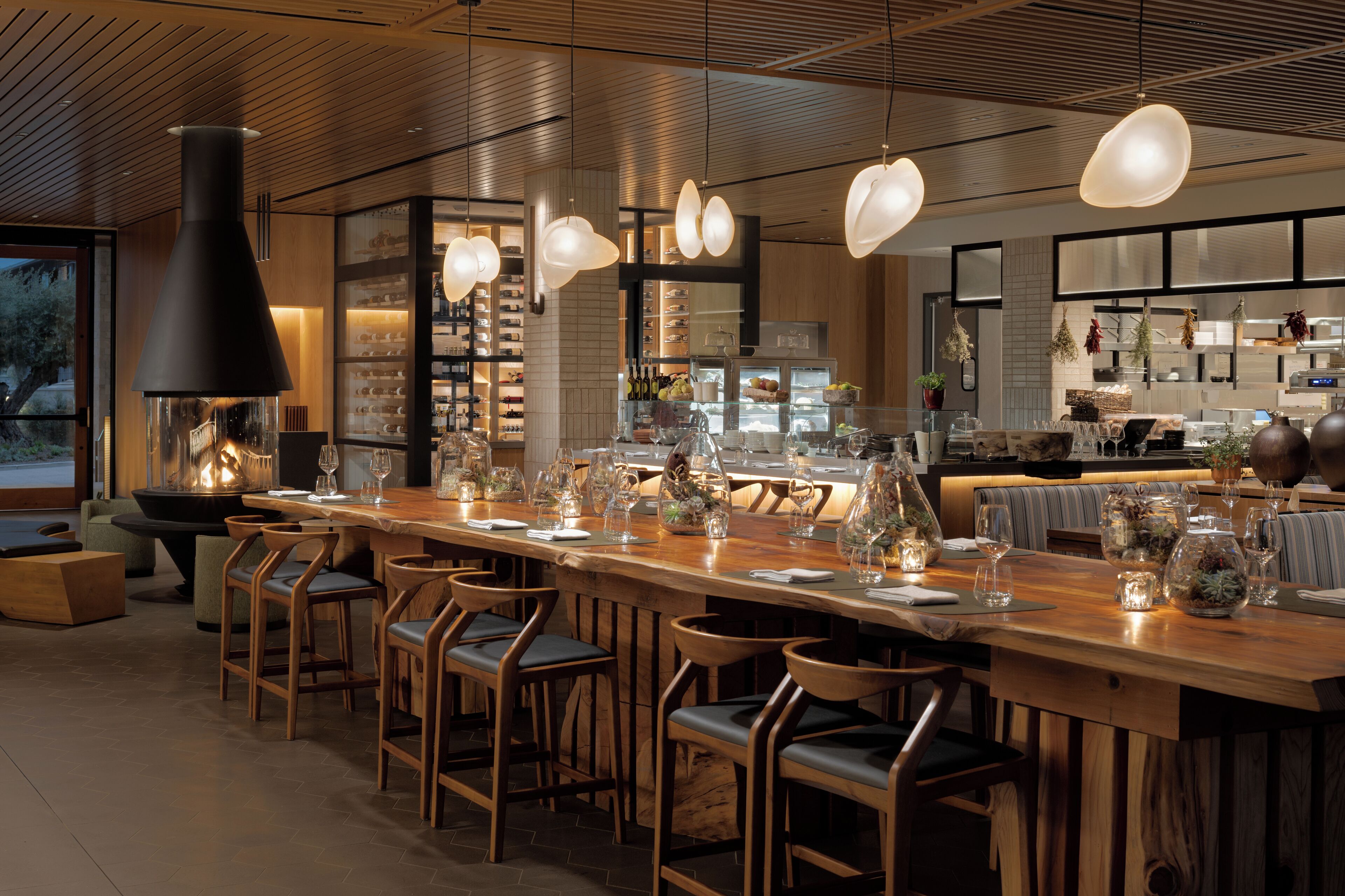 A restaurant with a long wooden bar, multiple seating areas, and a modern interior design.