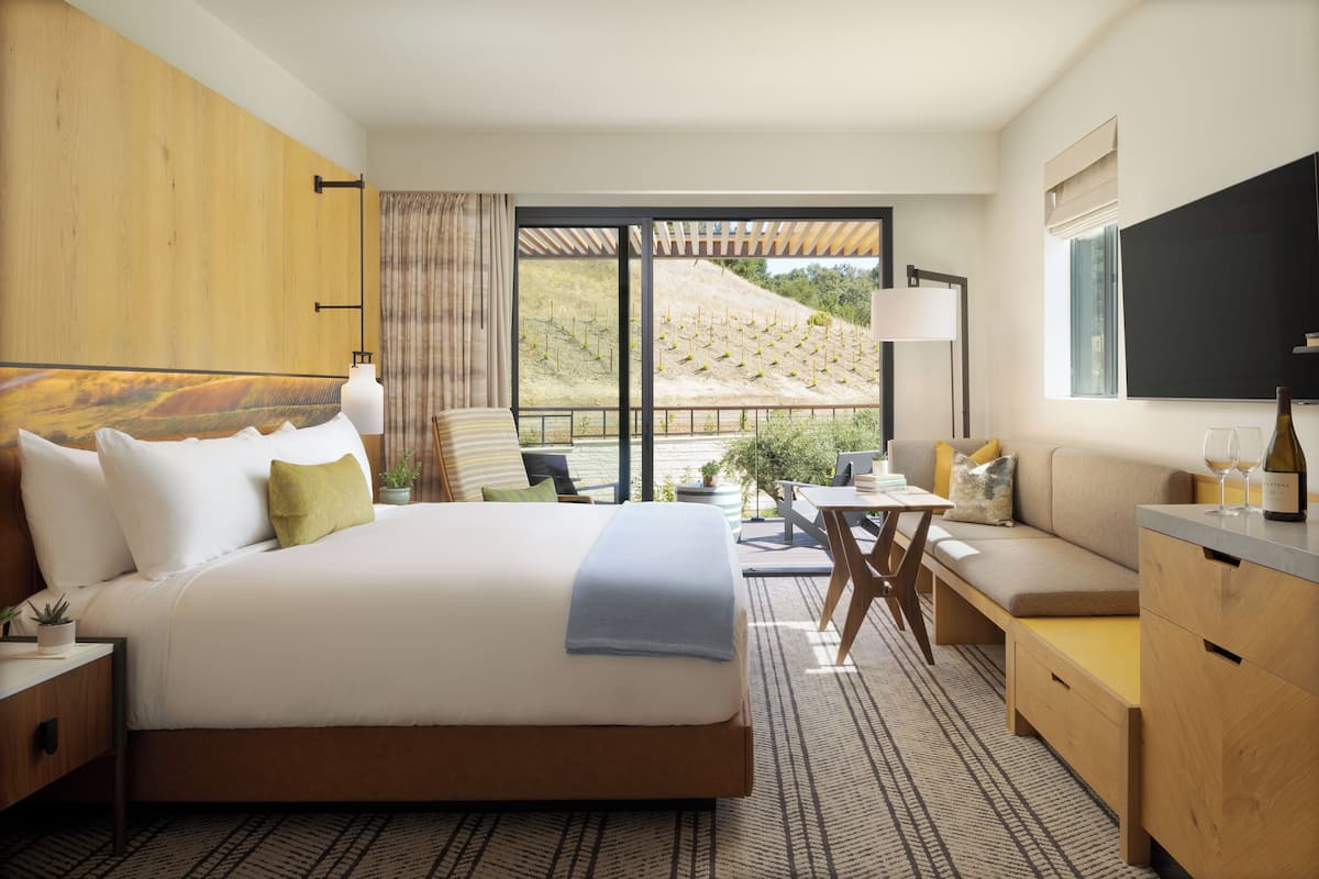A hotel room with a large bed, a sofa, a desk, and a TV.