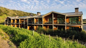 Une maison moderne à plusieurs étages, dotée de grandes fenêtres, d’un balcon et offrant une vue sur la verdure environnante.