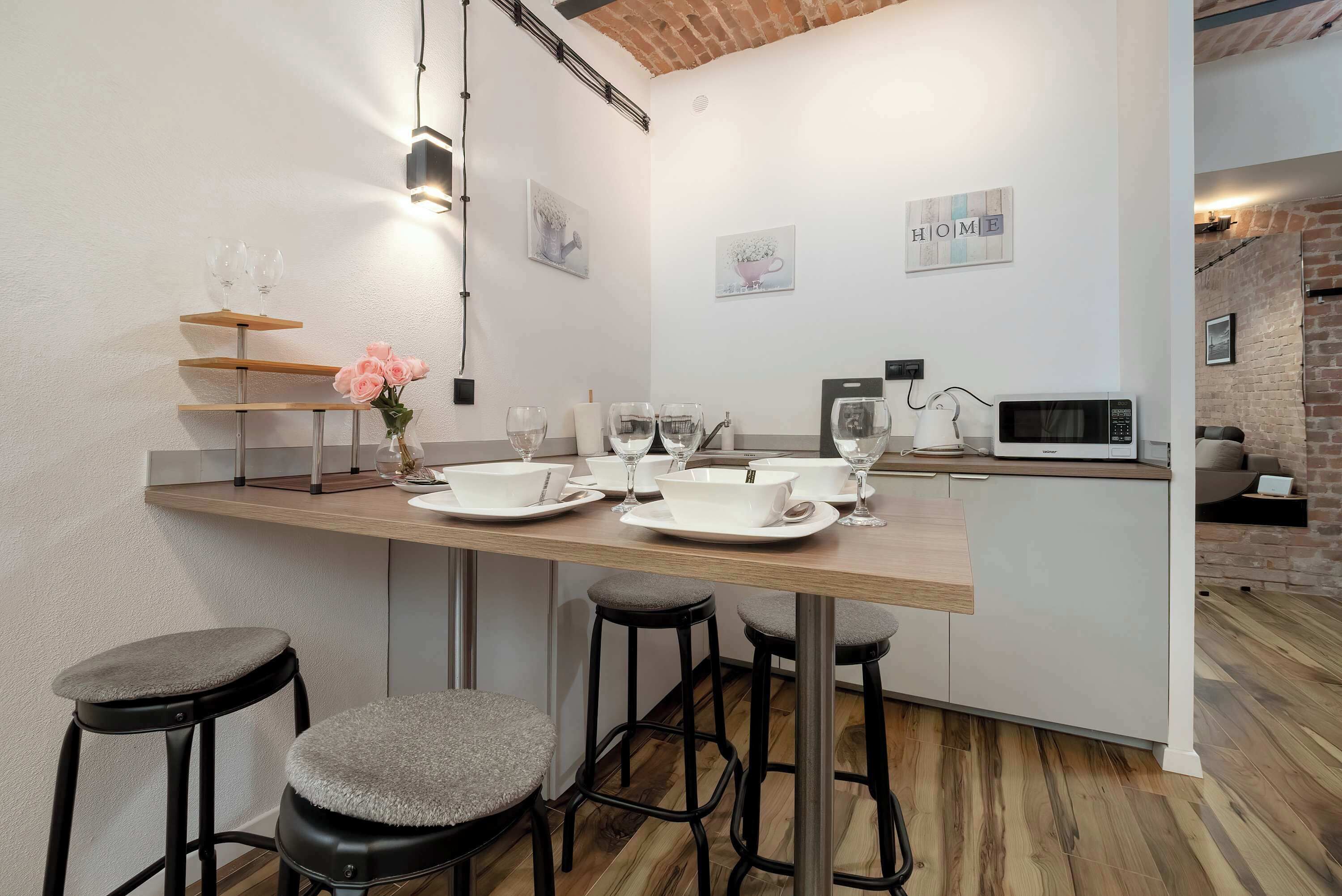 Una cocina moderna con una isla de madera, taburetes de bar y un microondas.