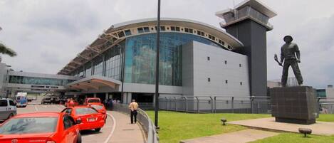 A modern building with a curved glass facade and a statue of a person on a pedestal.
