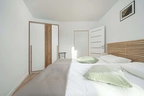A bedroom with a bed, a wooden headboard, a door, and a chair.