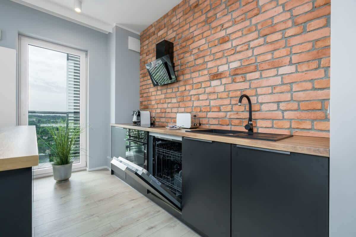 Een moderne keuken met een backsplash van baksteen, een ingebouwde oven en een raam met zonwering.