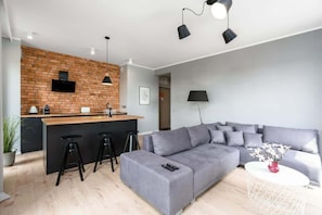 Un espace de vie moderne comprenant un coin cuisine, un canapé gris et une table basse ronde.