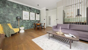 A modern living room with a sofa, coffee table, and a dining area with chairs and a table.