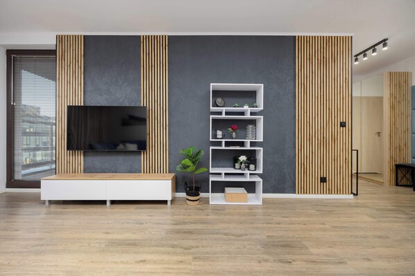 Una sala moderna con televisor de pantalla plana, listones de madera y estanterías empotradas.