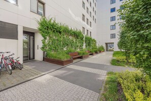 Un bâtiment moderne doté d’une allée pavée, de plantes vertes et de vélos garés à l’extérieur.