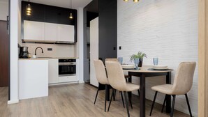 Une cuisine moderne avec des meubles blancs, un plan de travail noir et un coin repas comprenant une table et des chaises.