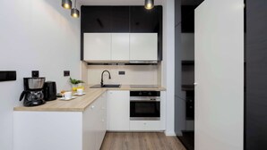 Une cuisine moderne avec des meubles blancs, un plan de travail noir, une machine à café et un évier.